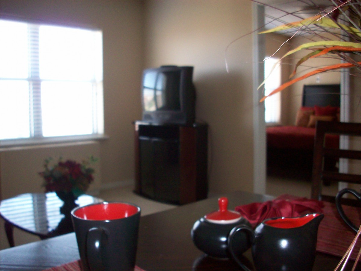 A cozy living room with a television and a stylish tea set near the window.