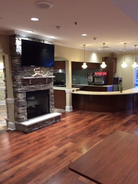 A modern living room with a stone fireplace, wood flooring, and a bar area.