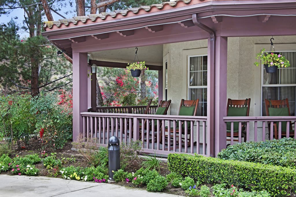 A charming house porch with a swing and vibrant garden.