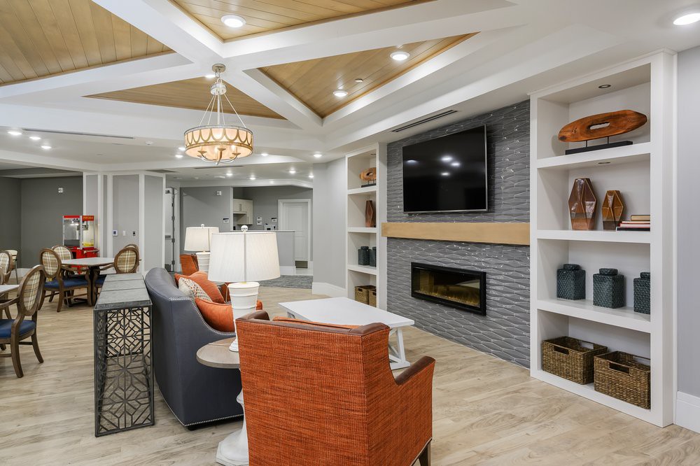 A stylish modern living room with a cozy seating arrangement, featuring a fireplace and television, accented by ceiling lights and decorative shelving.