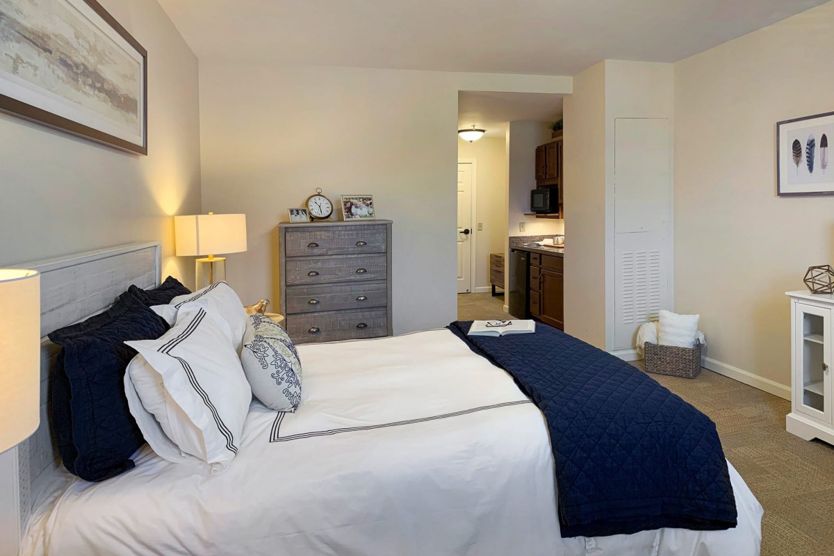 A cozy bedroom with stylish decor, featuring a neatly made bed with blue and white bedding.