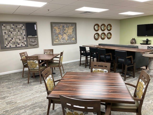 A cozy dining area with wooden tables and chairs, complemented by wall art and a small bar section.