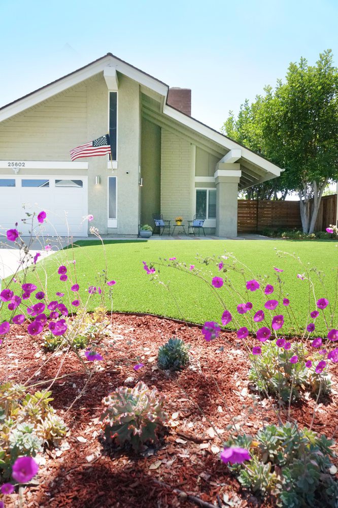 A suburban house with a well-maintained lawn and colorful garden in the foreground.