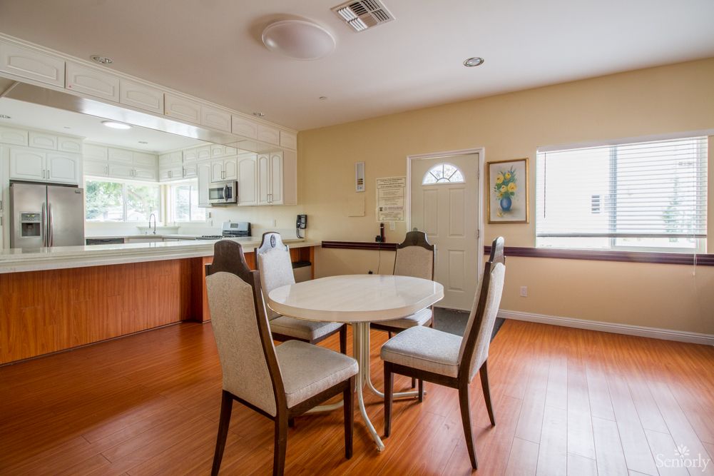 A cozy dining area with a round table and four chairs, adjacent to a modern kitchen.