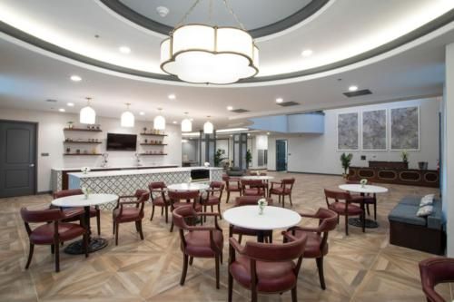 A modern dining area with stylish chairs and tables, featuring elegant lighting and a sleek bar counter in the background.