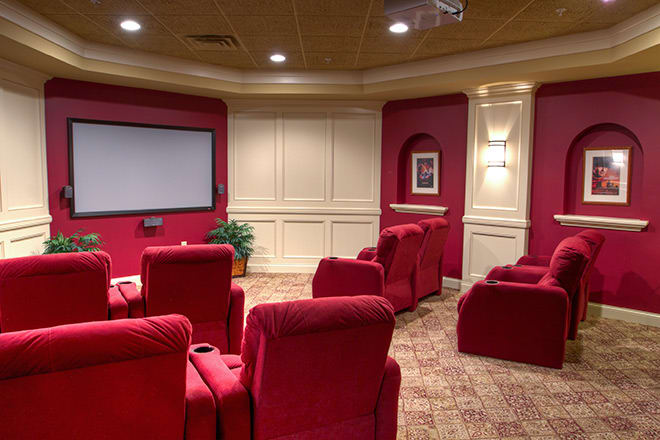 A luxurious home theater with red seats and a large projection screen.