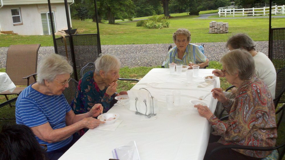 A group of elderly people enjoying a meal together at an outdoor table.