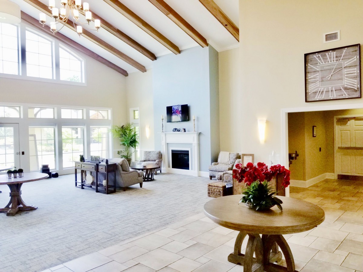 A spacious and elegantly designed living room featuring high ceilings with wooden beams, abundant natural light, and a modern fireplace.