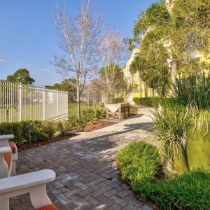 A serene garden pathway lined with benches and surrounded by lush greenery.