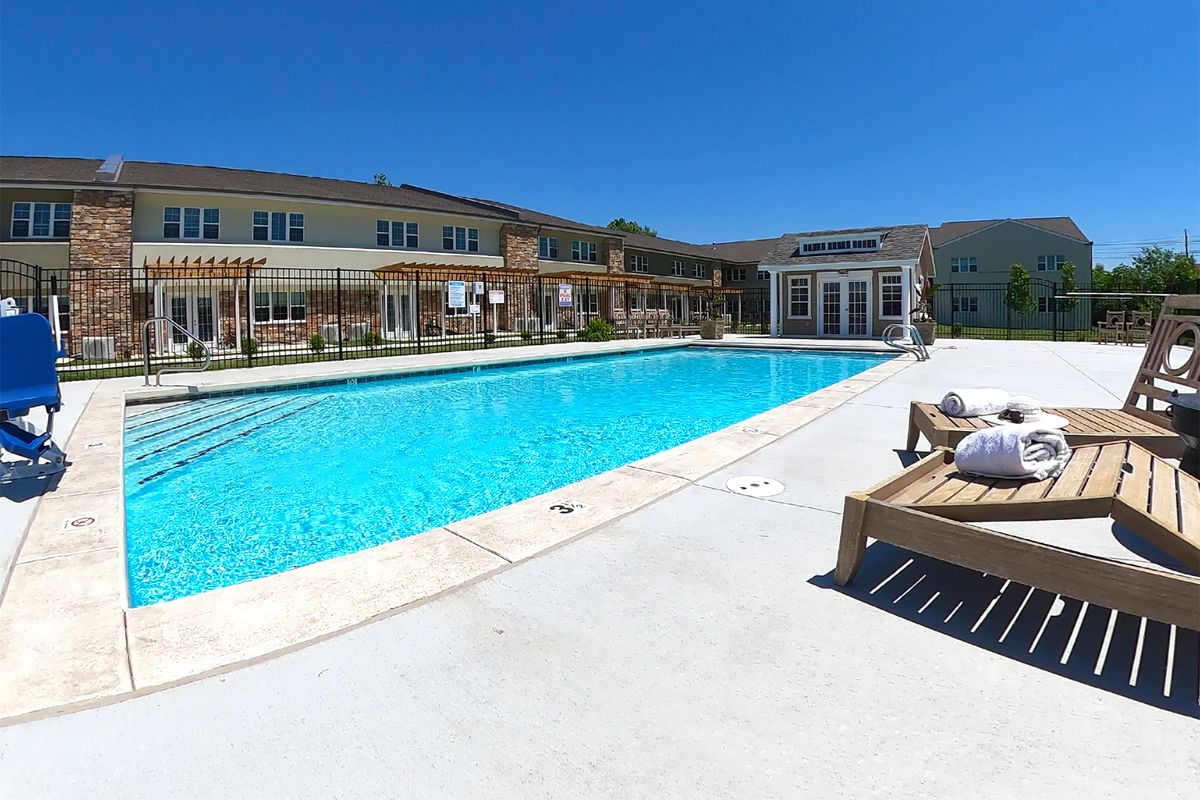 A sunny day at a residential outdoor swimming pool with lounge chairs.
