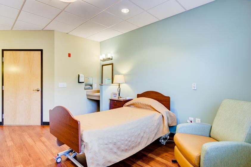 A well-lit hospital room with a single bed and basic furnishings.