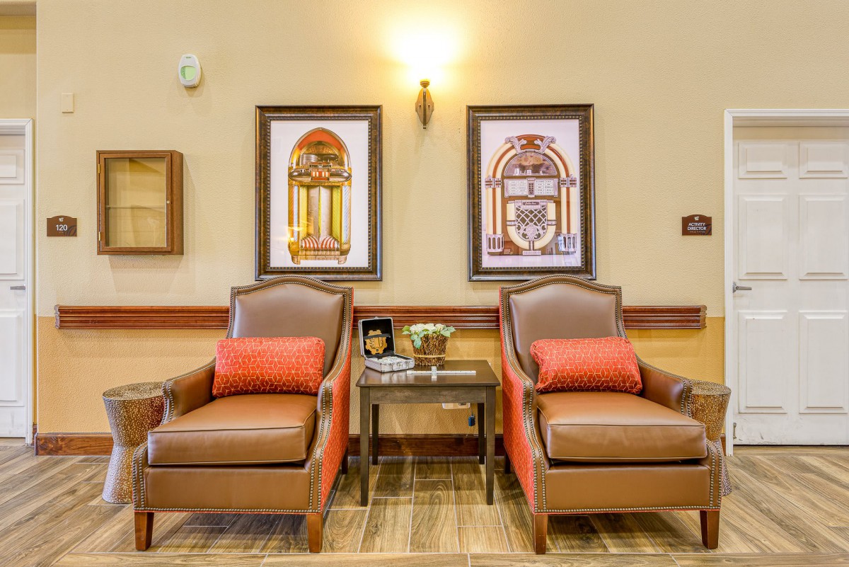 A cozy seating area with two leather chairs, a small table, and framed artwork on the wall.