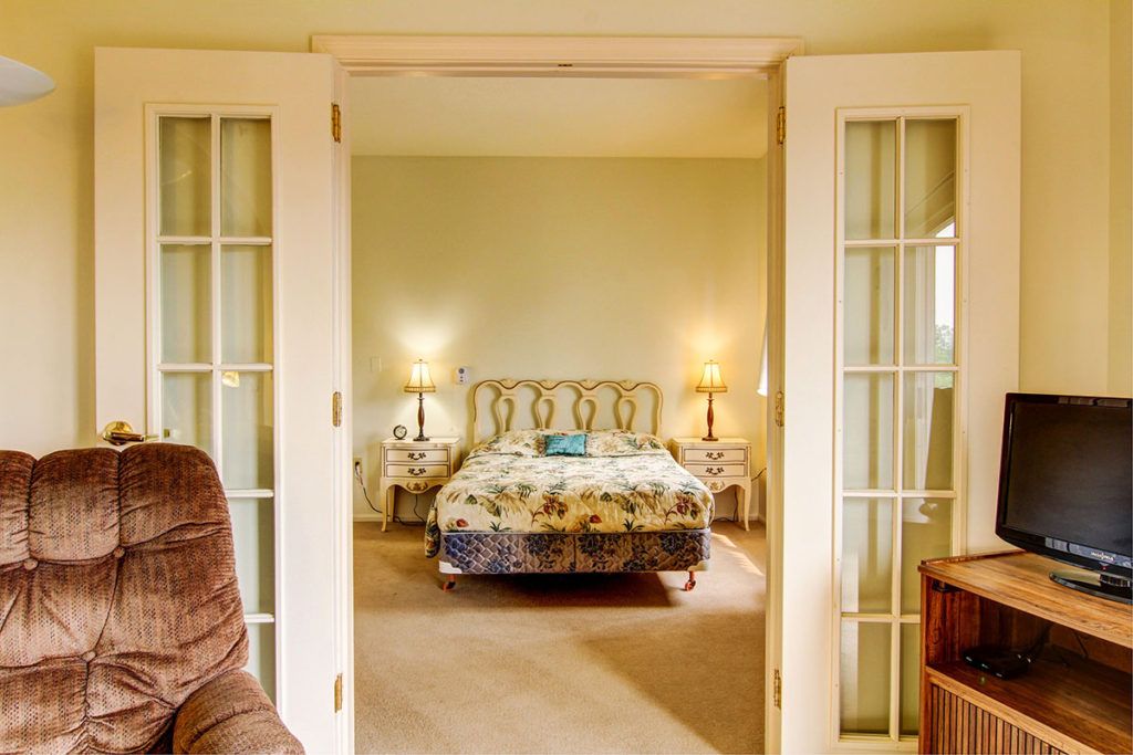 Cozy traditional bedroom with glass doors and warm lighting.