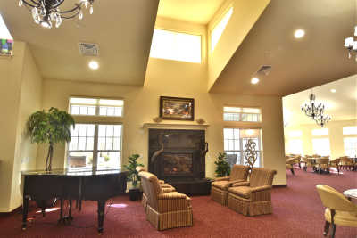A spacious living room with comfortable seating, a piano, and a fireplace.