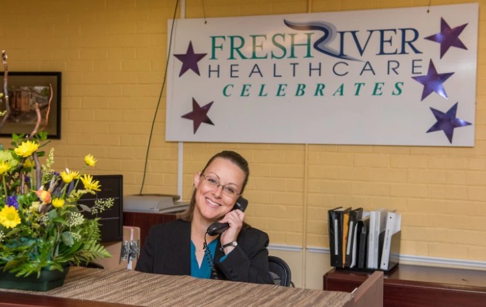 A receptionist talking on the phone in a healthcare office setting.