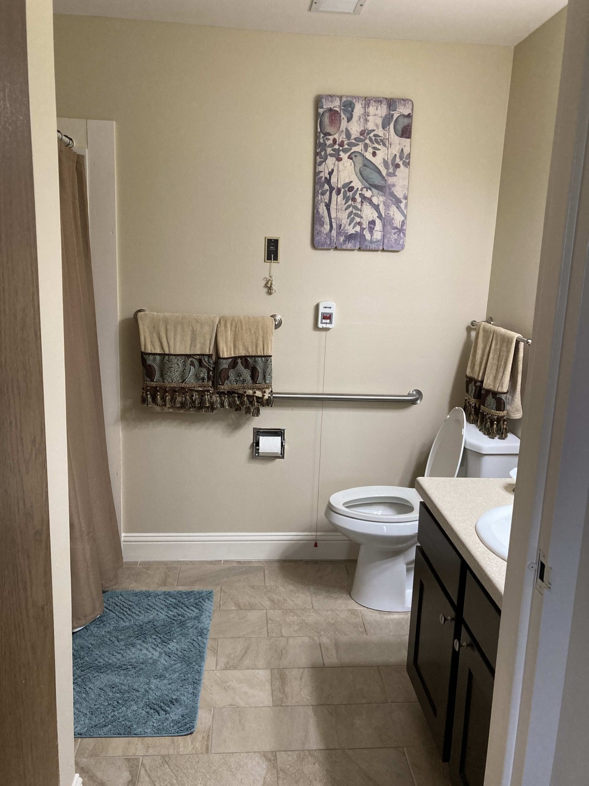 A well-organized bathroom with a toilet, sink, towels, and a decorative wall hanging.