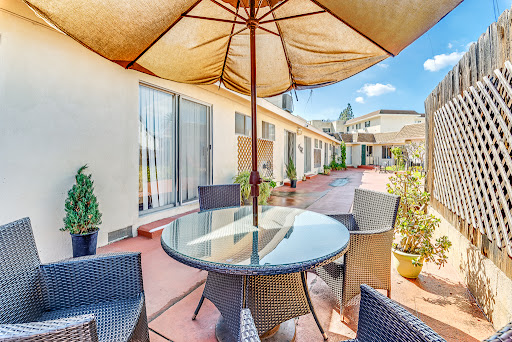 A serene outdoor patio set up with a glass table, stylish chairs, and a protective umbrella.