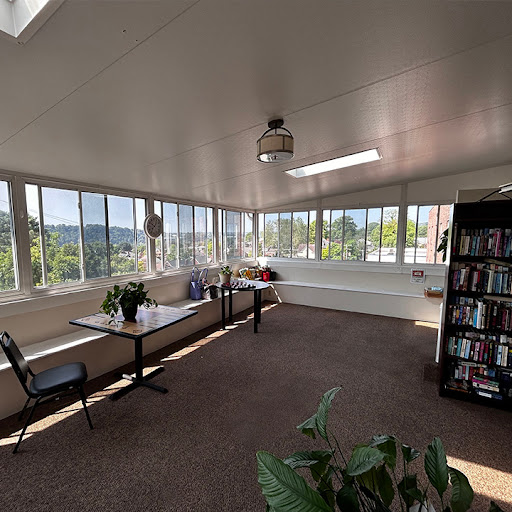 A bright and airy sunroom designed as a cozy reading area, featuring large windows and comfortable seating.