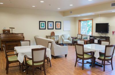 A bright and spacious dining area with tables, chairs, and sofas, adorned with artwork on the walls.