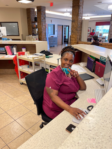 A friendly receptionist at her desk, smiling while working on her computer.