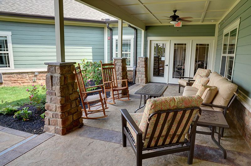 A cozy covered patio with rocking chairs and cushioned seats for relaxation.