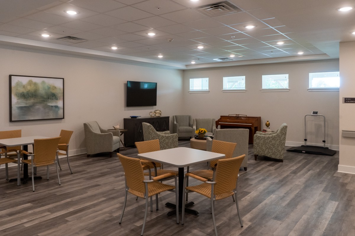 A modern lounge area with comfortable seating, a television, and a piano.
