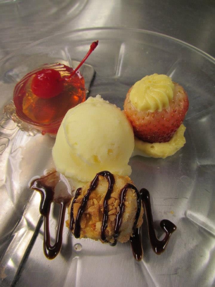 A beautifully plated dessert featuring ice cream, topped with chocolate sauce and garnished with a cherry.