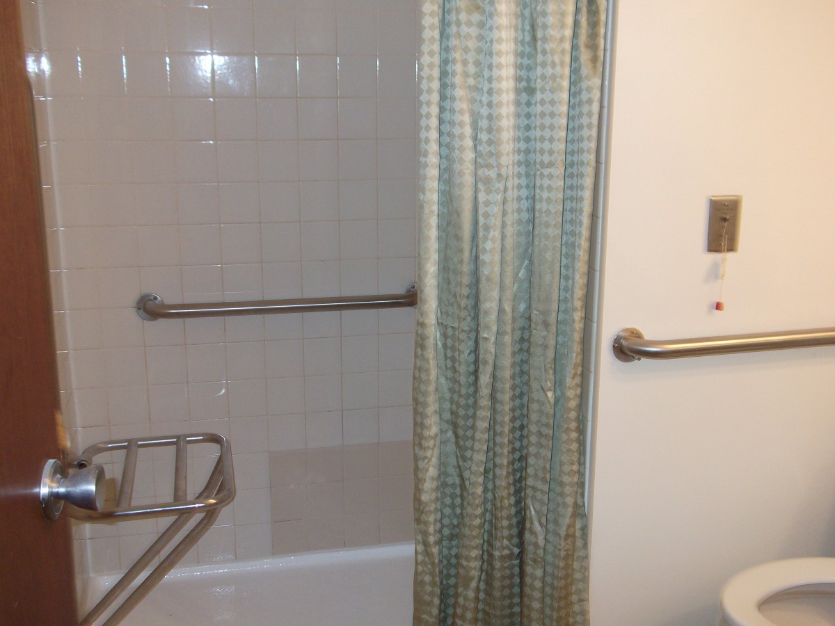 A bathroom featuring a shower with a patterned curtain, tiled walls, and metal fixtures.