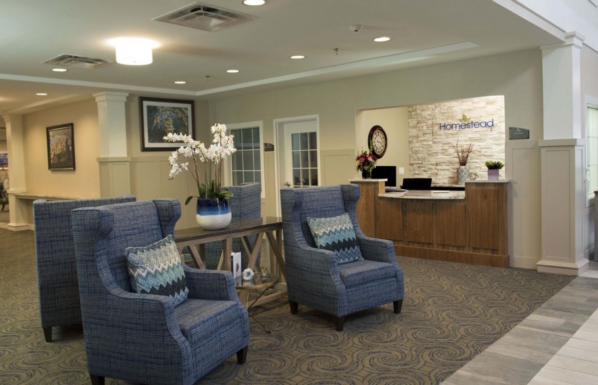A cozy lobby with blue armchairs and a reception desk.
