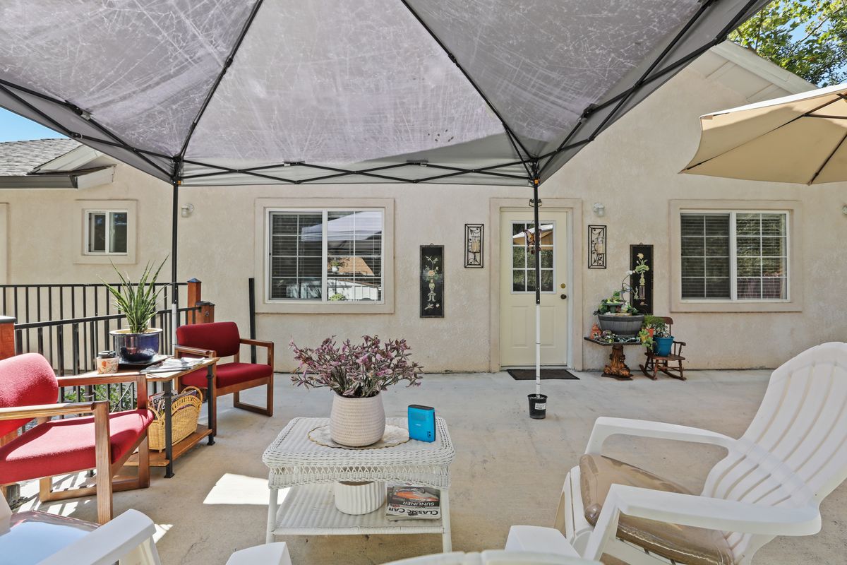 A cozy patio setup with a canopy, outdoor seating, and potted plants.