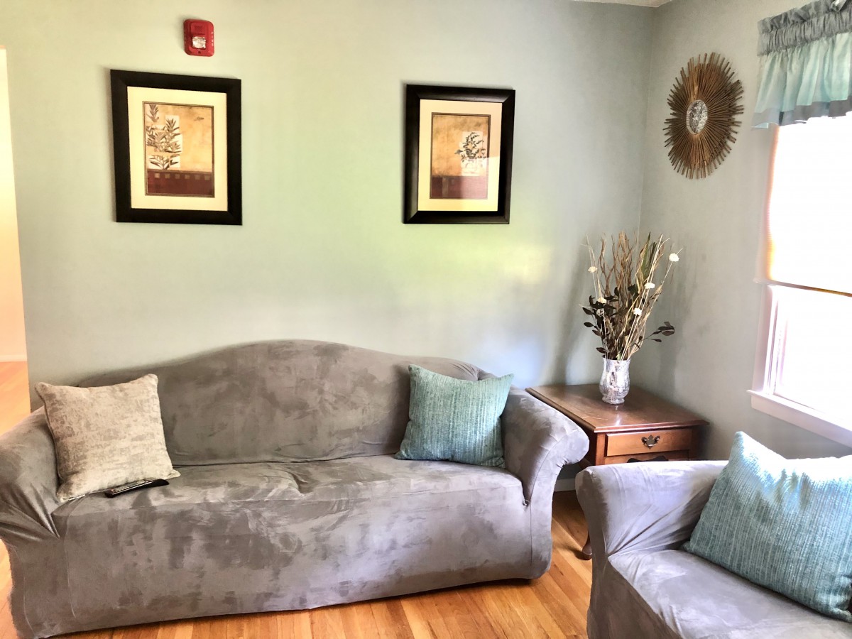 A cozy living room with a gray sofa, complemented by wall art and decorative pillows.