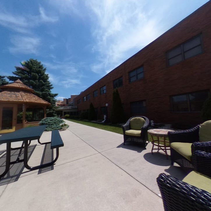 A sunny outdoor patio with seating and a view of the building.