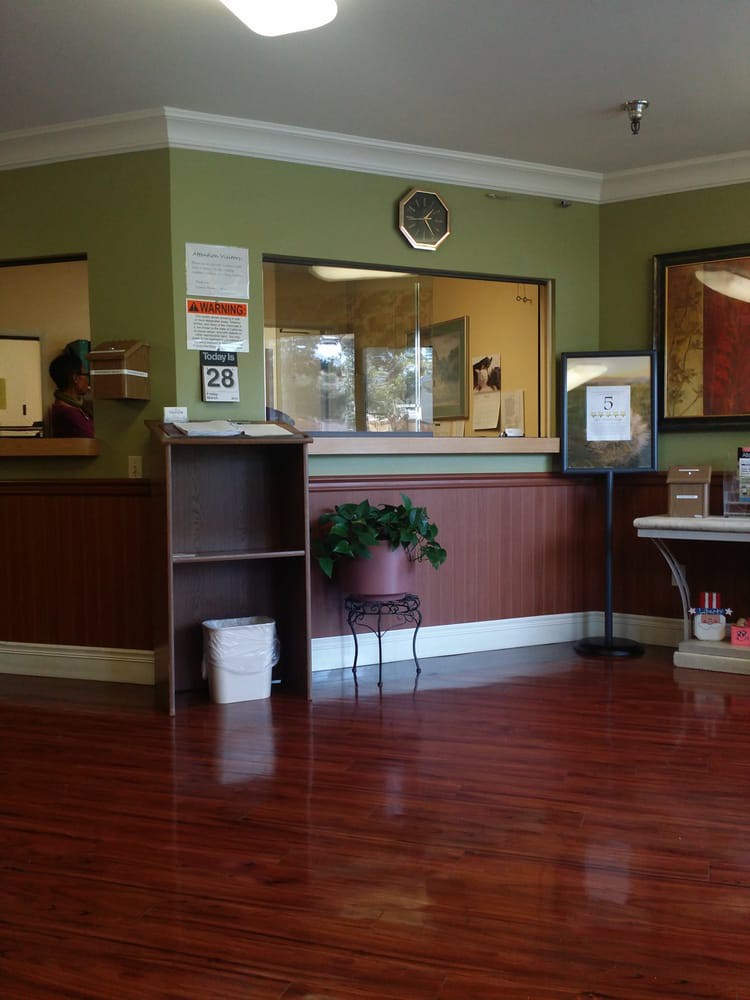 A reception area with a desk, clock, and plant.