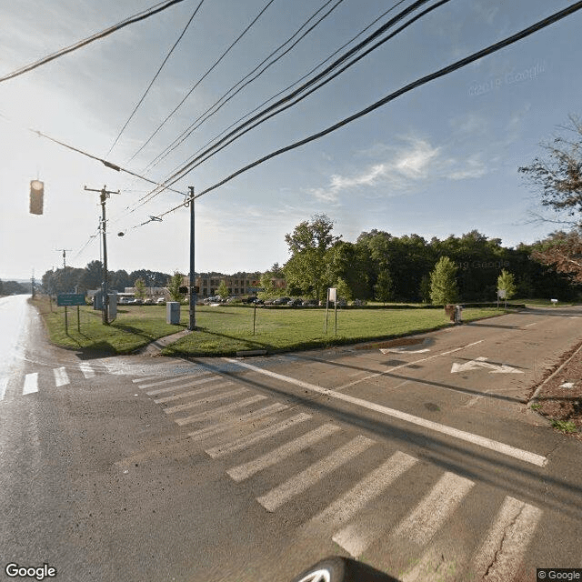 A street intersection with a crosswalk and traffic lights near a fenced park area.