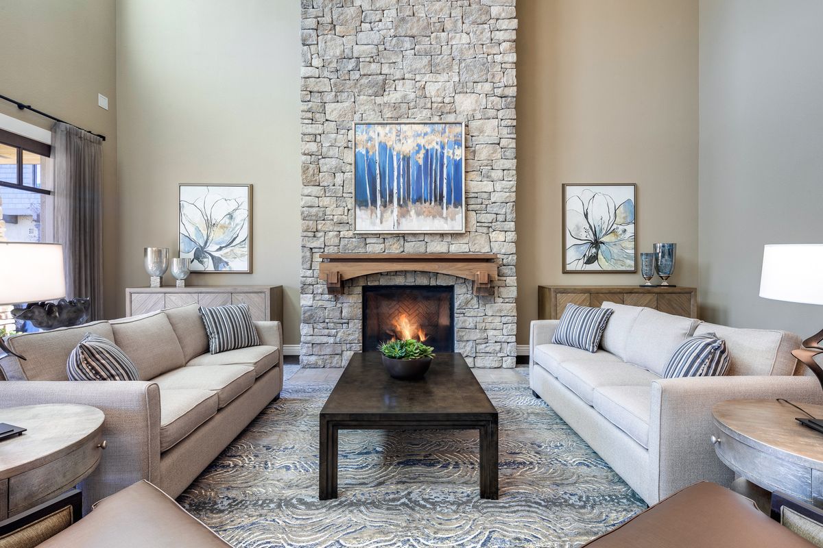 A cozy living room with a stone fireplace, featuring modern decor and neutral-colored sofas.