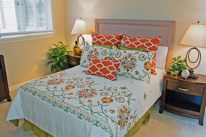 A cozy bedroom with decorative pillows and floral bedding.