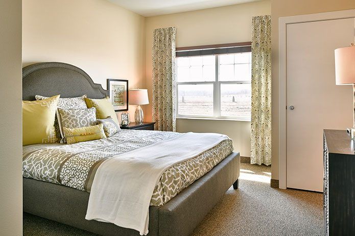 A cozy bedroom interior with a neatly made bed and a window letting in natural light.