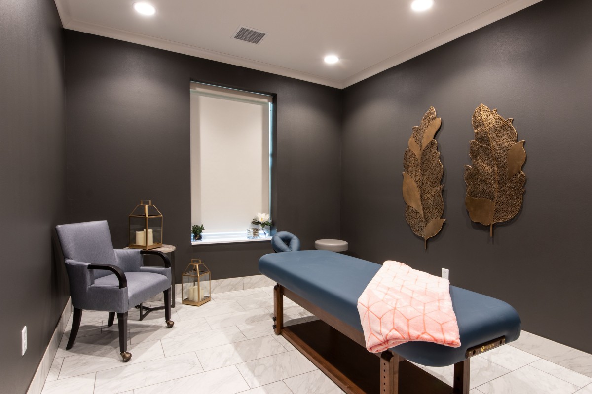 A modern therapy room featuring a massage table, relaxing decor, and comfortable seating.