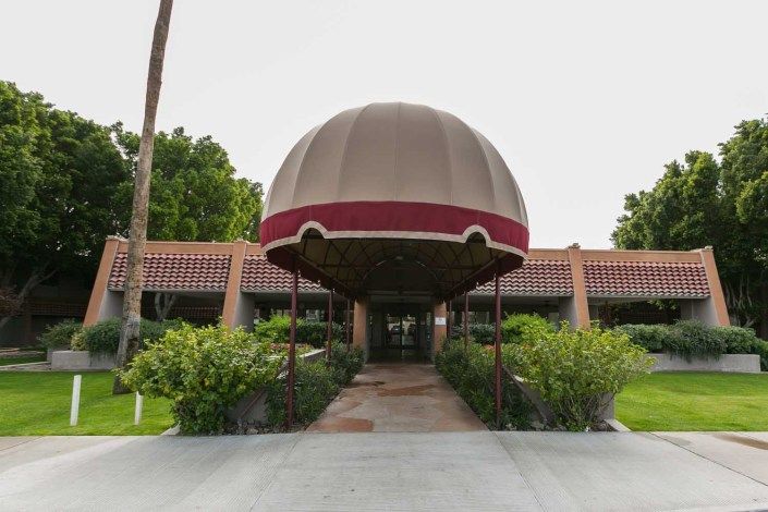 A building entrance with a large dome-shaped canopy and surrounding greenery.