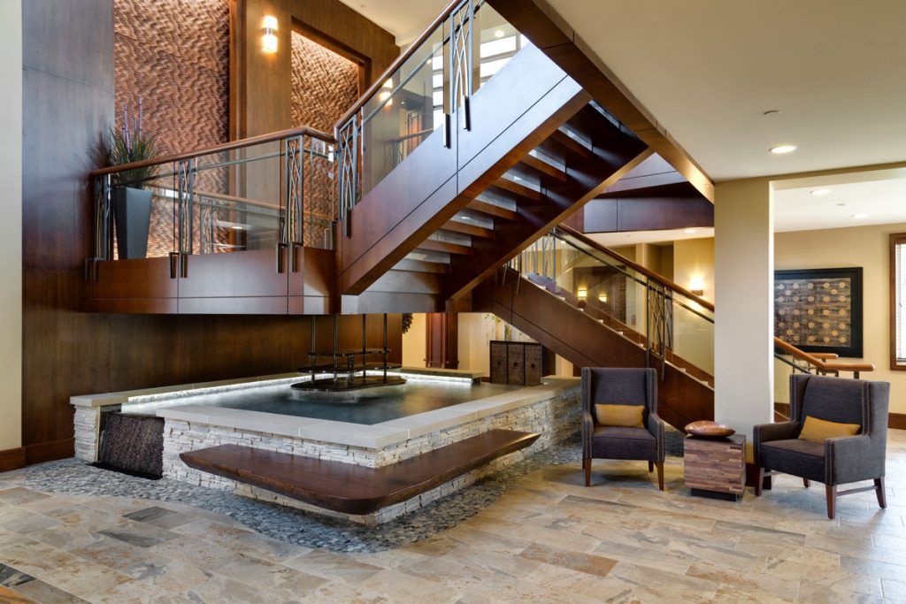A modern lobby featuring a stylish wooden staircase and seating area.