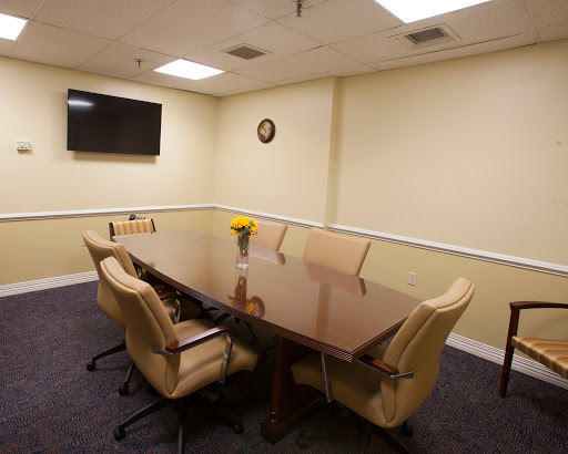A well-furnished conference room equipped with a large table, chairs, and a television for meetings.