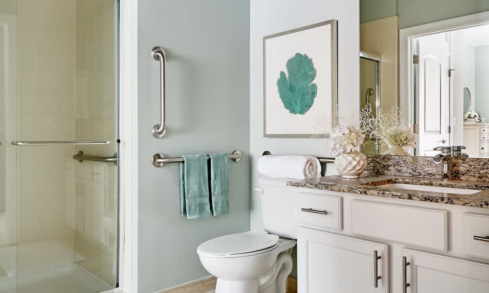 A modern bathroom featuring a toilet, towels, and decorative artwork on the wall.