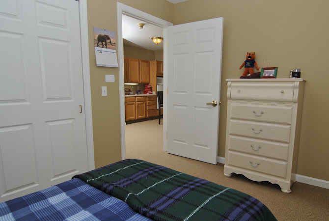 A cozy bedroom with a view into the kitchen through an open door.