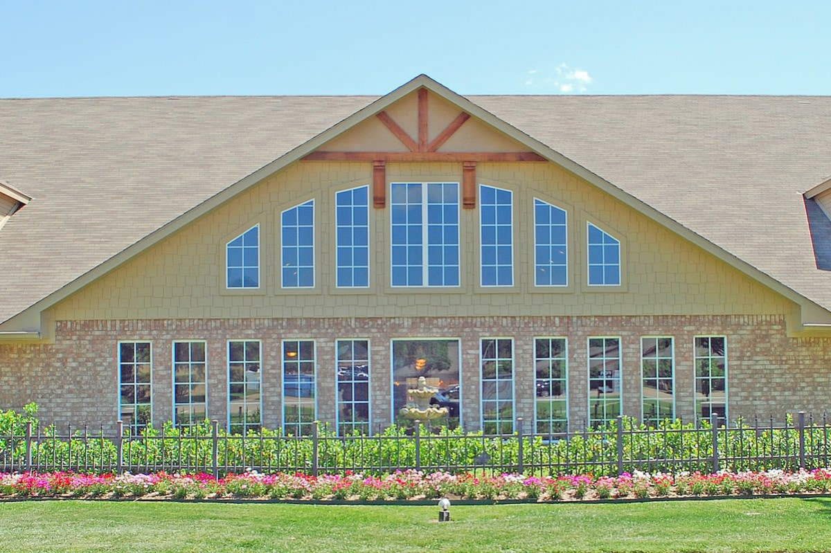 A large house with prominent windows and a well-maintained garden in the foreground.