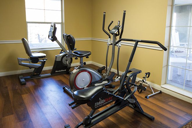 A small home gym with exercise equipment including an elliptical machine and a stationary bike.