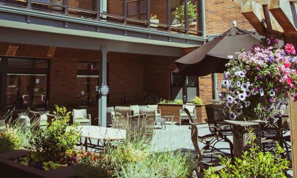 A cozy outdoor patio area with seating and plants under a sunny sky.