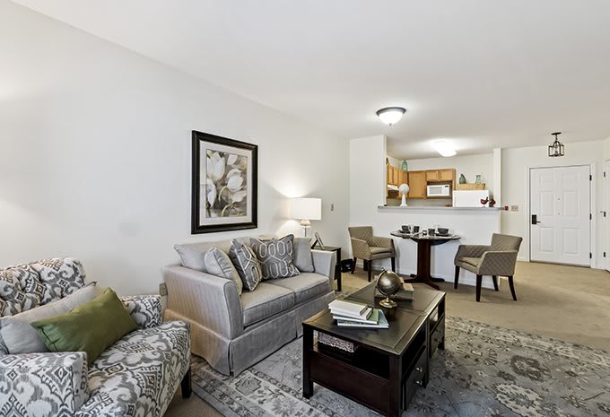 A modern living room with a sofa, coffee table, and adjacent dining area leading to the kitchen.