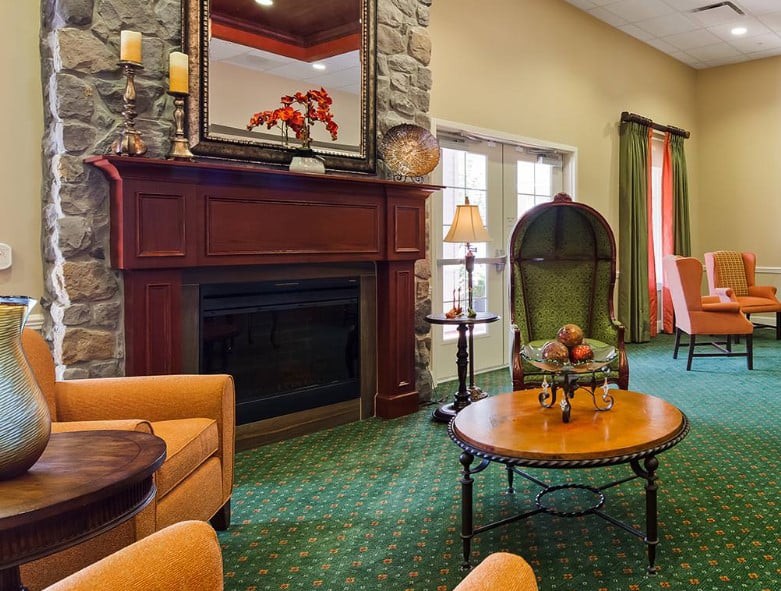 A cozy living room interior featuring a stone fireplace, comfortable seating, and elegant decor.