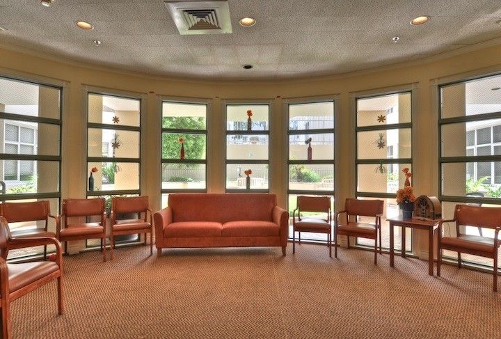 A spacious and well-lit waiting room with a sofa and chairs arranged in front of large windows.