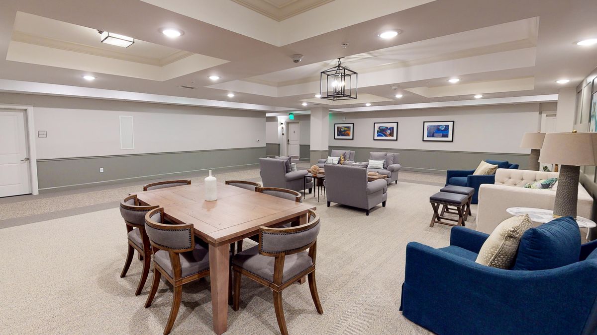 A modern meeting room featuring a large table, comfortable chairs, and lounge seating in a well-lit space.